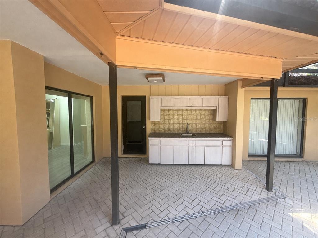 A covered outdoor patio features a kitchenette with white cabinets, a sink, and tiled backsplash — 6701 PEMBERTON VIEW DRIVE, SEFFNER, FL