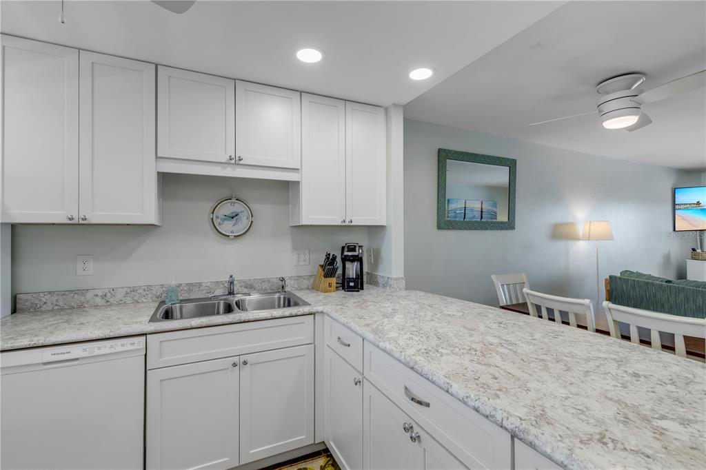 A kitchen features white cabinets, a light-colored stone countertop, a double sink, and recessed lighting — 4151 S ATLANTIC AVENUE UNIT 3030, NEW SMYRNA BEACH, FL