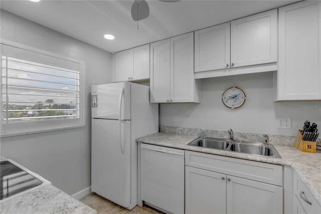 A kitchen features white cabinets, a white refrigerator, a double sink, and granite countertops — 4151 S ATLANTIC AVENUE UNIT 3030, NEW SMYRNA BEACH, FL
