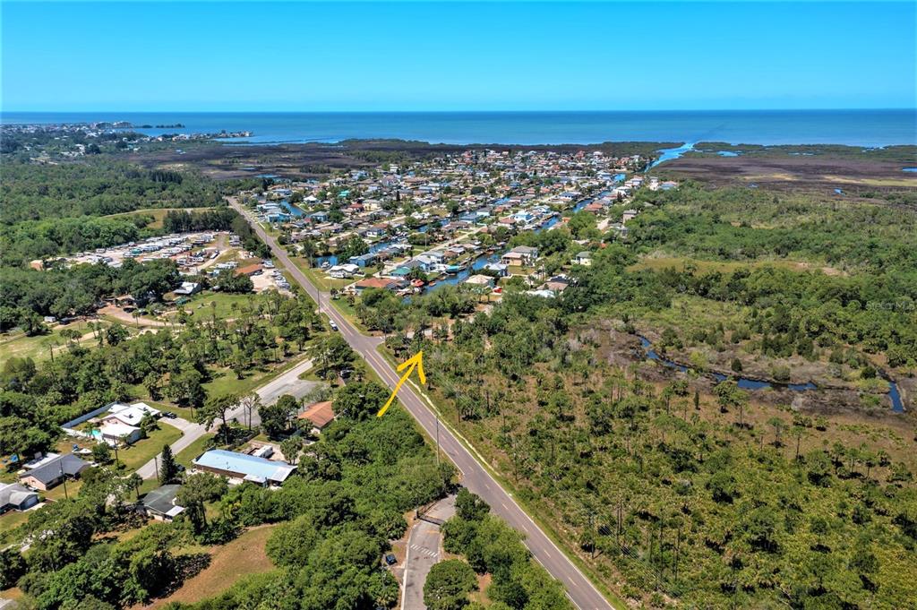 An aerial view shows a coastal neighborhood with houses, a road, and surrounding natural vegetation — 0 GULF WAY, HUDSON, FL