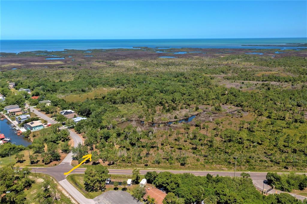 An aerial view shows a wooded lot near a coastal waterway and a paved road — 0 GULF WAY, HUDSON, FL