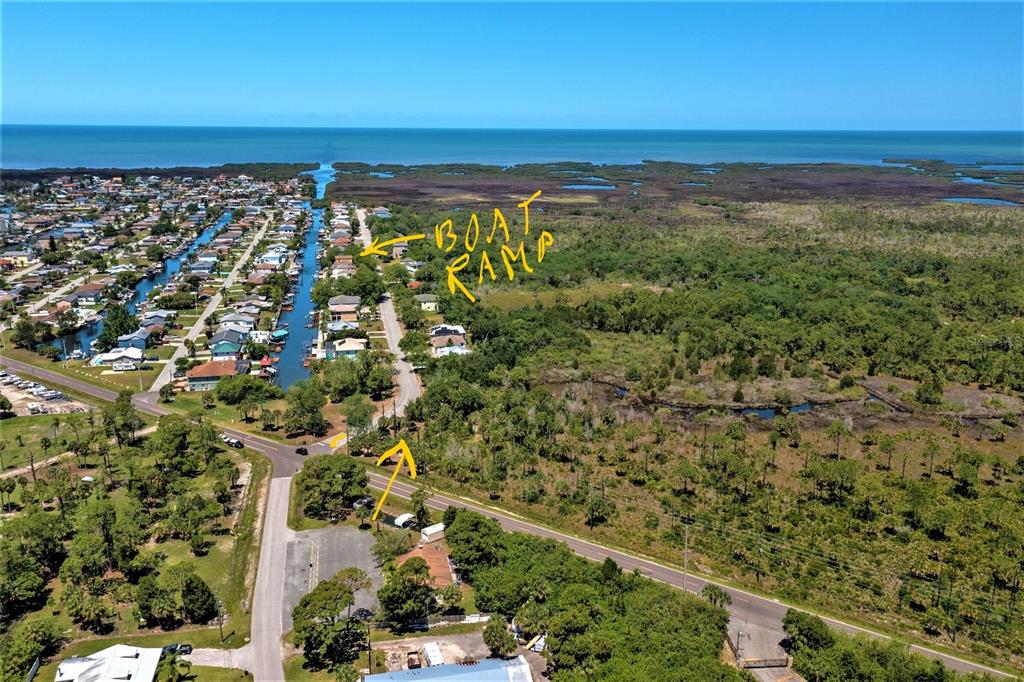 An aerial view shows a residential canal community with a boat ramp and surrounding vegetation — 0 GULF WAY, HUDSON, FL