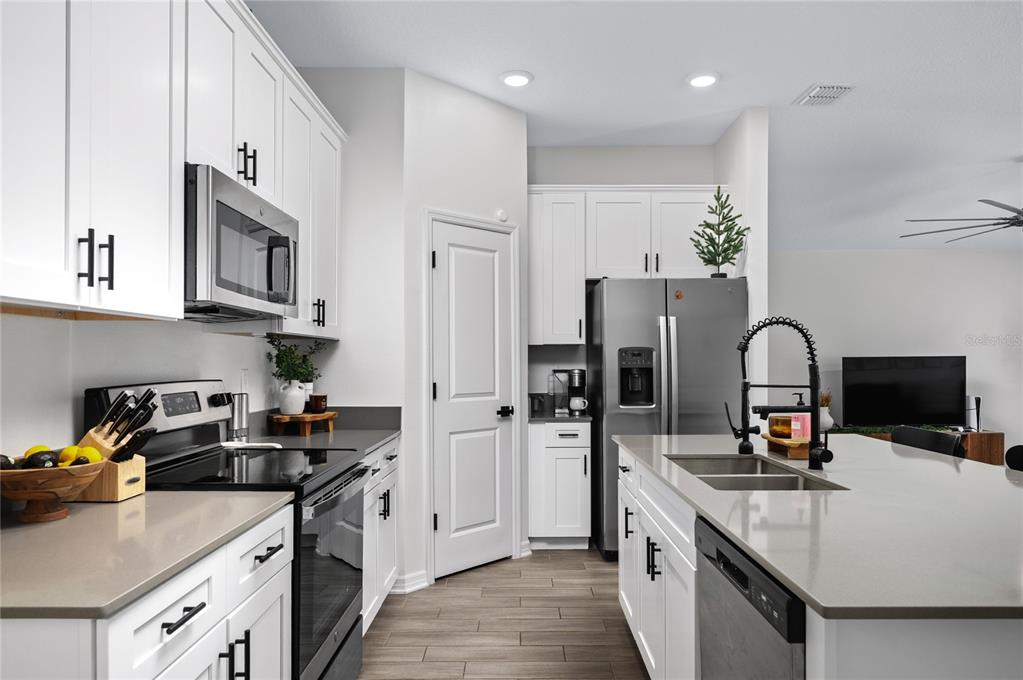 A modern kitchen features white cabinets, stainless steel appliances, a kitchen island, and gray countertops — 2518 HOPTREE LANE, EDGEWATER, FL