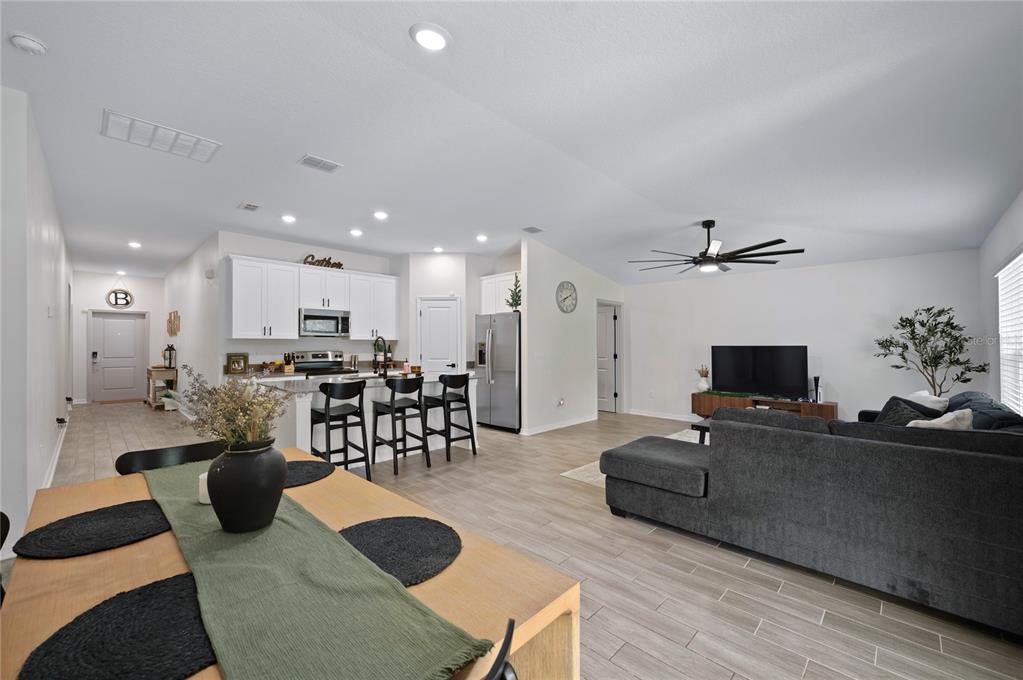 An open-concept living area features a kitchen with white cabinets, an island, and a dining space — 2518 HOPTREE LANE, EDGEWATER, FL