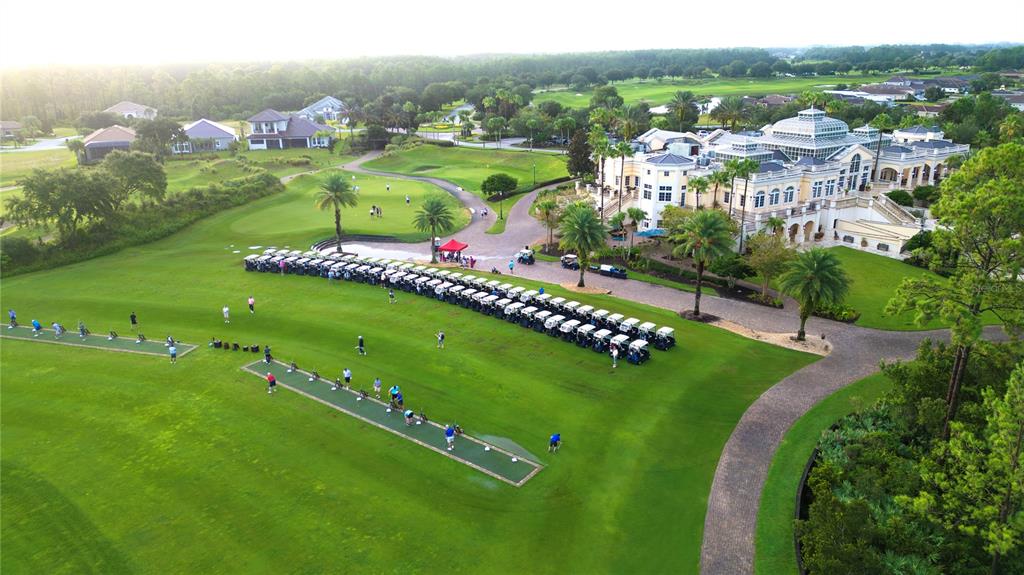 An aerial view shows a golf driving range with parked carts and a large clubhouse building — 105 HICKORY COURT, PALM COAST, FL