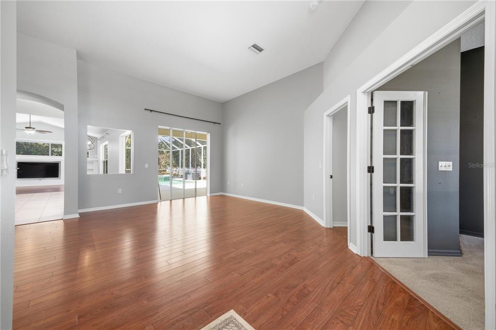 A living room with wood-look flooring, high ceilings, a sliding glass door, and French doors — 3209 PARTRIDGE POINT TRAIL, VALRICO, FL