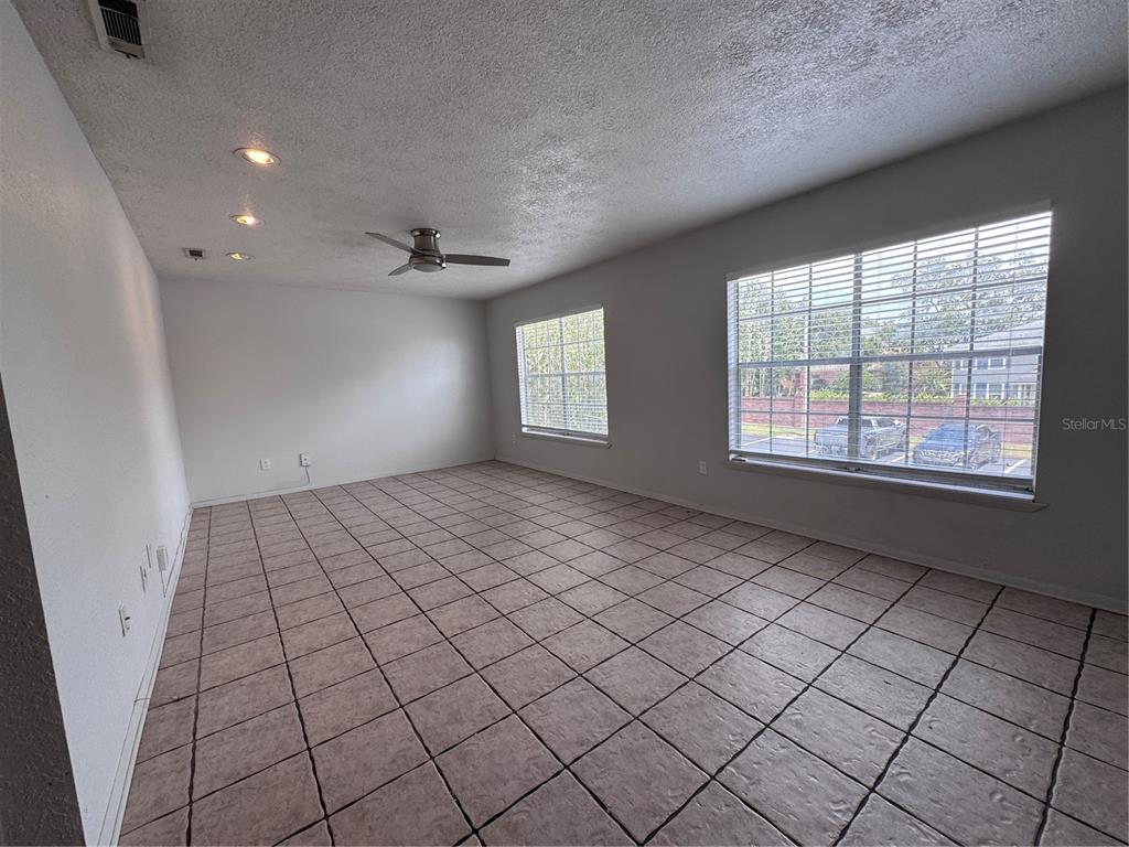An empty room features light-colored tile flooring, a ceiling fan, recessed lighting, and two windows — 5343 HANSEL AVENUE UNIT F4, ORLANDO, FL