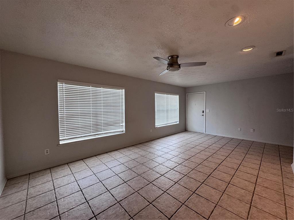 An empty room features light-colored tile flooring, two windows with blinds, and a ceiling fan — 5343 HANSEL AVENUE UNIT F4, ORLANDO, FL