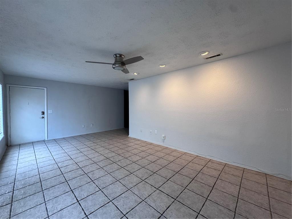 An empty room features light-colored tile flooring, a ceiling fan, and recessed lighting — 5343 HANSEL AVENUE UNIT F4, ORLANDO, FL