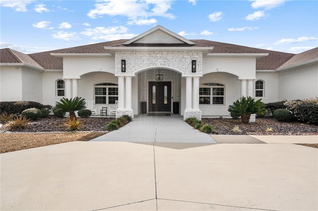 A white house with a stone-accented entryway, columns, and a concrete driveway — 6160 W HIGHWAY 326, OCALA, FL