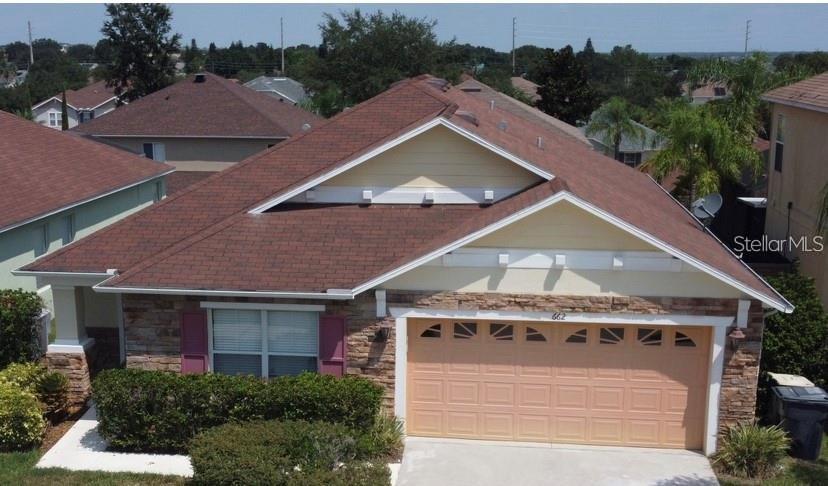 An elevated view of a single-story house with a brown shingled roof and stone facade — 662 ROSSELLI BOULEVARD, DAVENPORT, FL