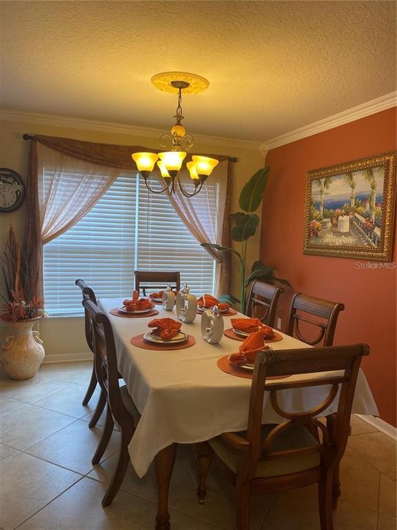 A dining room features a table set for six, a chandelier, and an orange accent wall — 662 ROSSELLI BOULEVARD, DAVENPORT, FL