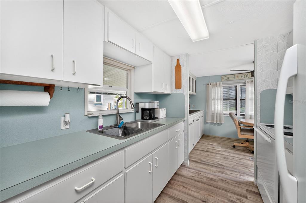 A kitchen features white cabinets, light blue countertops, and wood-look flooring — 7494 DANVERS CIRCLE, PORT CHARLOTTE, FL