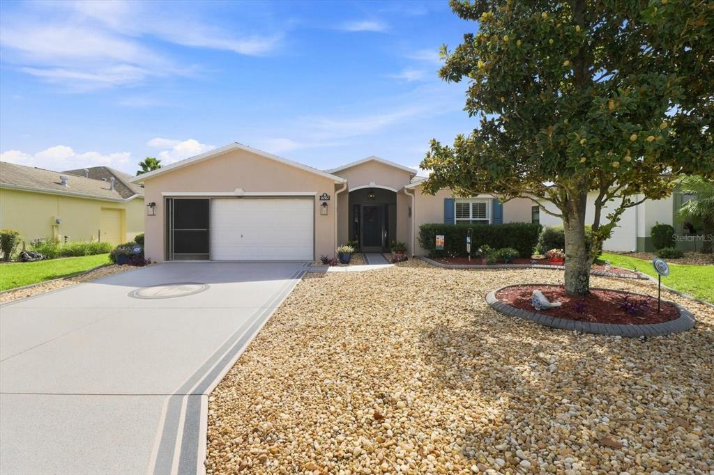 A single-story house with a white garage door, gravel front yard, and a large tree — 16367 SW 13TH TERRACE, OCALA, FL