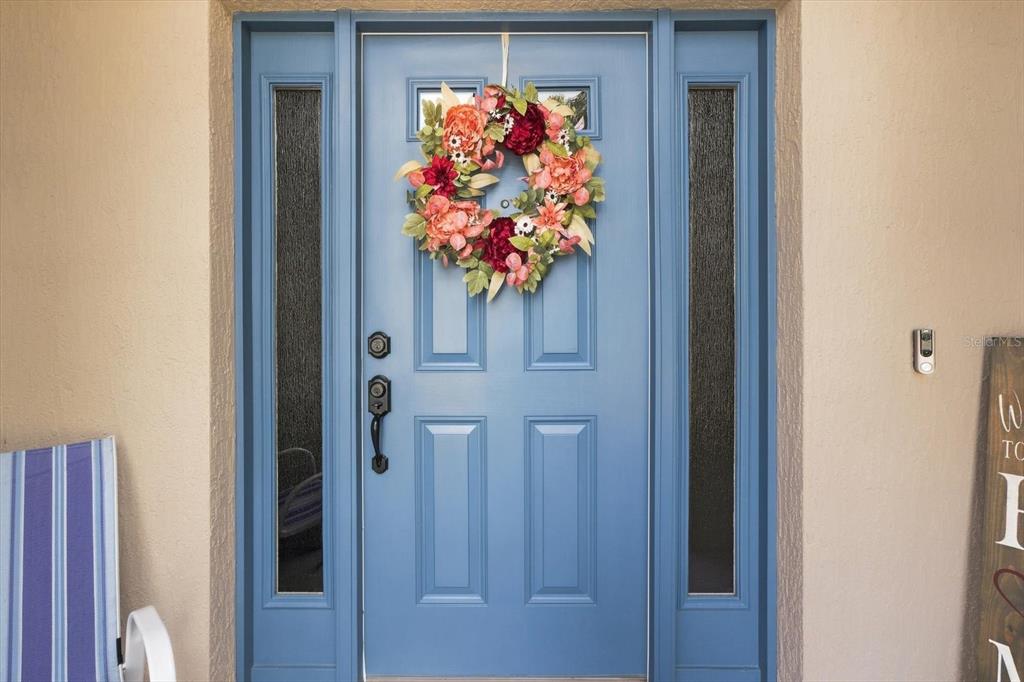 A blue front door with a floral wreath is flanked by two vertical glass sidelights — 16367 SW 13TH TERRACE, OCALA, FL