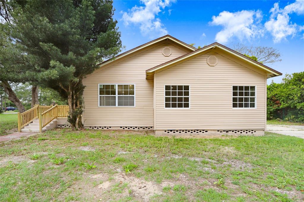A tan, single-story house with vinyl siding, a wooden deck, and a grass yard — 310 S DELANEY AVENUE, AVON PARK, FL