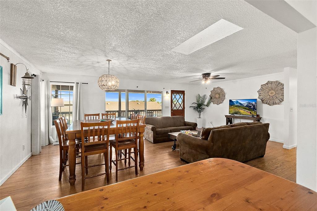 An open-concept living and dining area features wood flooring, brown sofas, and a wooden table — 32 ARMAND BEACH DRIVE, PALM COAST, FL
