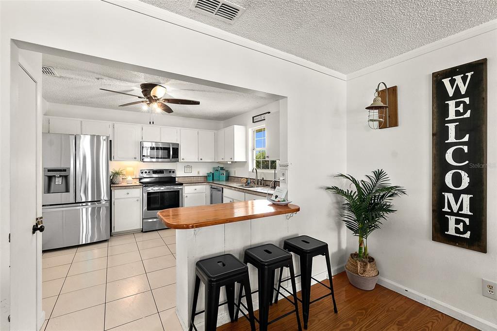 A kitchen with white cabinets and stainless steel appliances opens to a dining area — 32 ARMAND BEACH DRIVE, PALM COAST, FL