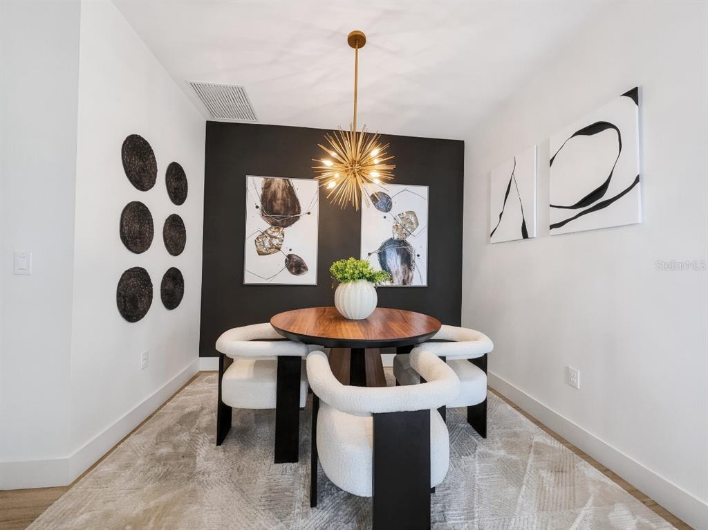 A dining room features a round wooden table, four white chairs, and a gold chandelier — 8841 OCEANA WAY, NAPLES, FL