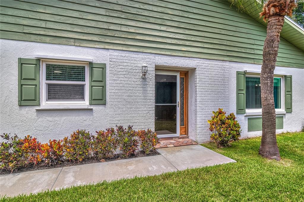 The exterior of a house features white brick, green siding, green shutters, and a palm tree — 3217 MCMATH DRIVE, PALM HARBOR, FL
