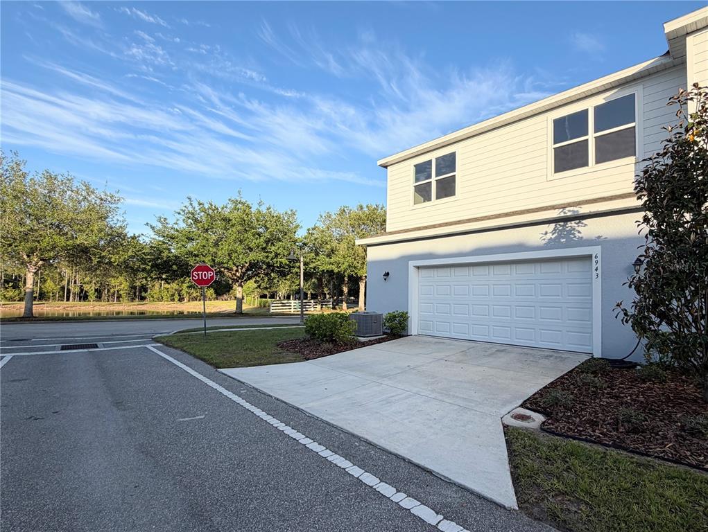 A two-story house exterior features a white garage door, a concrete driveway, and a stop sign — 6943 FIVE OAKS DRIVE, HARMONY, FL