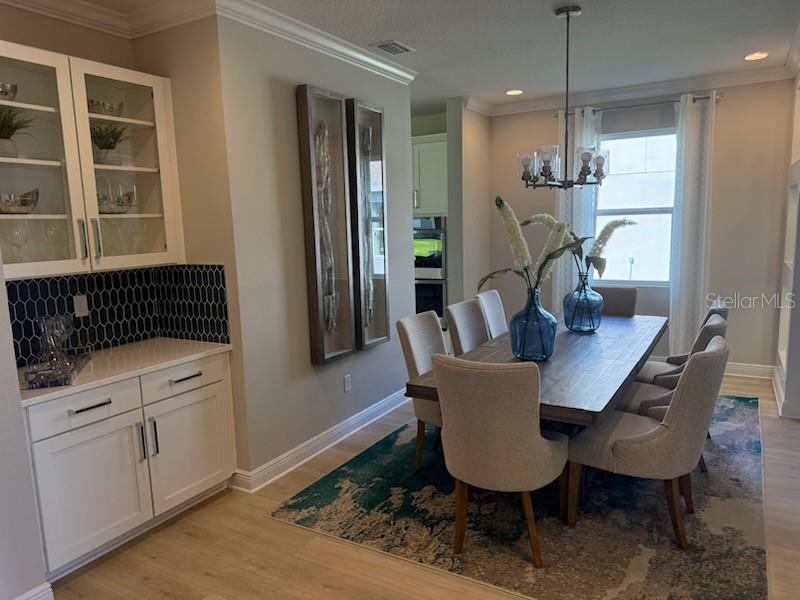 A dining room features a wooden table, upholstered chairs, a blue rug, and built-in cabinetry — 5288 OBSIDIAN GATE DRIVE, MOUNT DORA, FL
