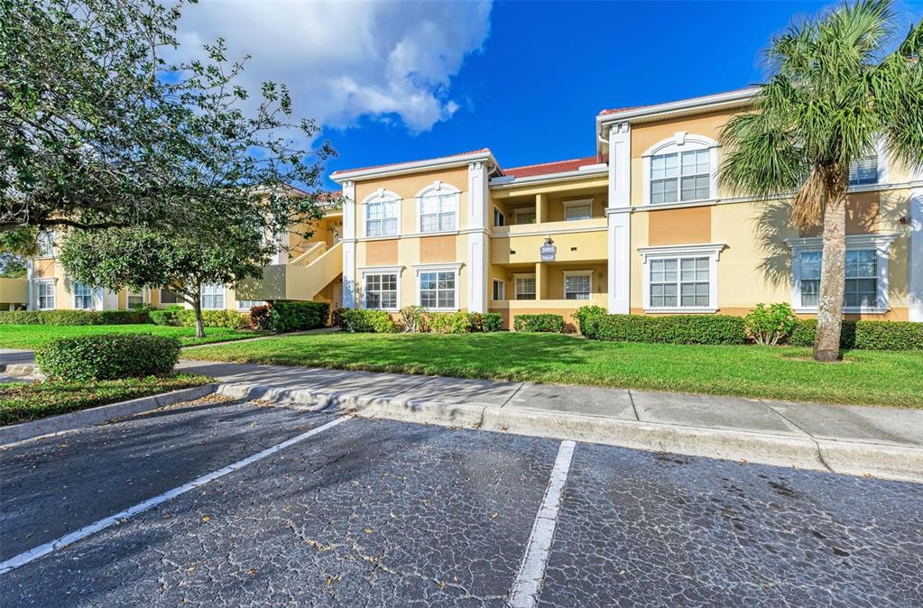 A multi-story apartment building with yellow stucco walls, white trim, and a palm tree — 3005 CHIANTI COURT UNIT 1003, SARASOTA, FL