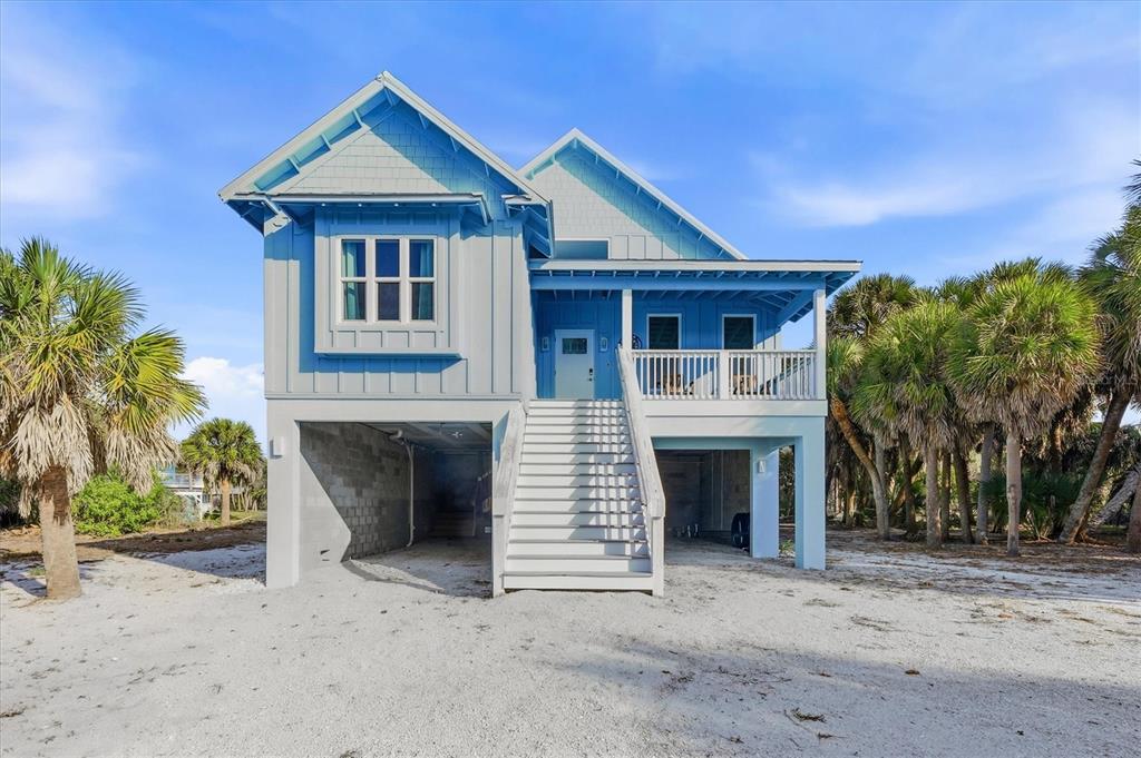 A light blue elevated house with a white staircase stands on a sandy lot — 19 LEMON BAY LANE, PLACIDA, FL