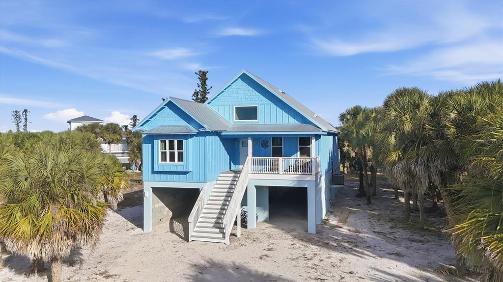 A bright blue elevated house with a metal roof stands on a sandy lot — 19 LEMON BAY LANE, PLACIDA, FL