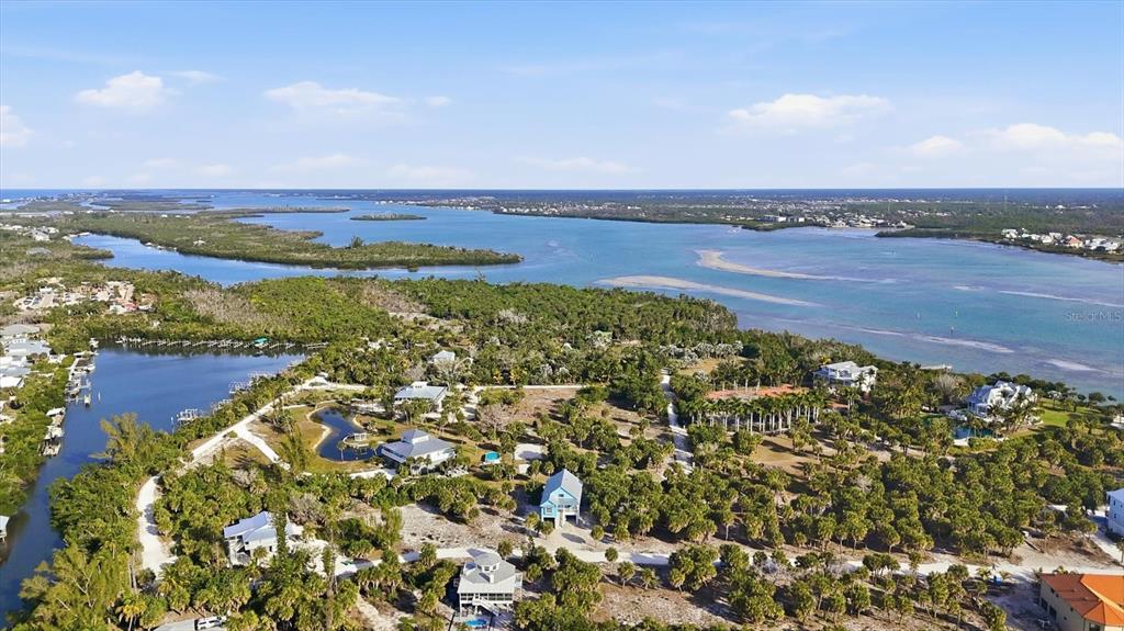 An aerial view shows several houses nestled among trees near a coastal waterway — 19 LEMON BAY LANE, PLACIDA, FL