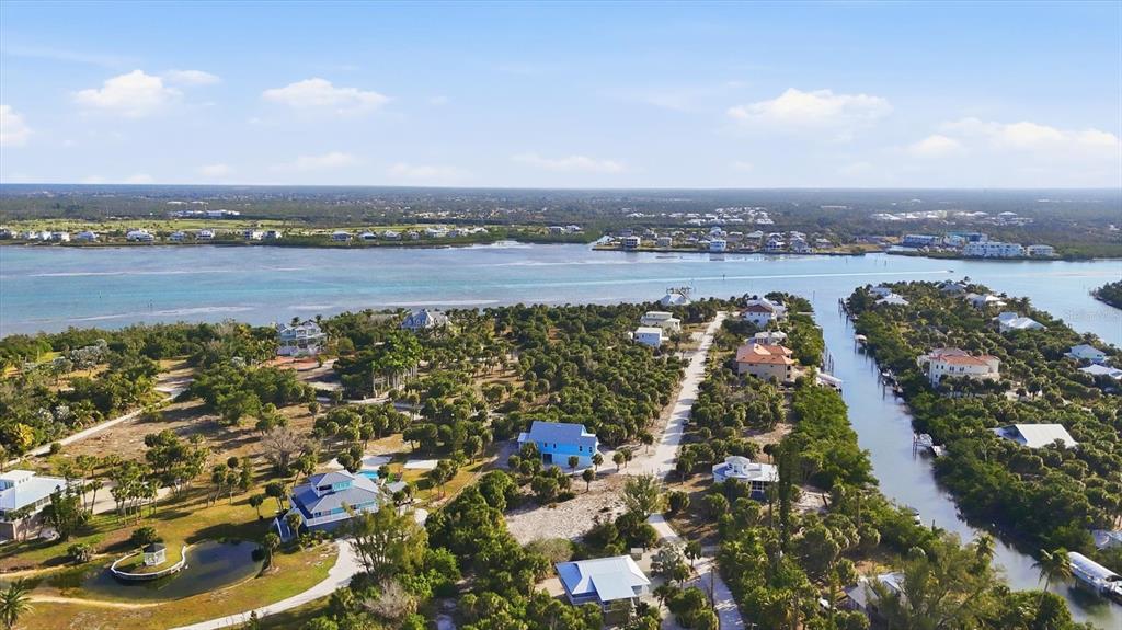 An aerial view shows houses nestled among trees near a canal and a large bay — 19 LEMON BAY LANE, PLACIDA, FL