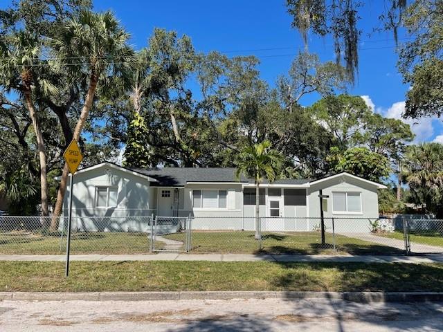A single-story house with light-colored siding and a dark roof sits behind a chain-link fence — 741 28TH AVENUE S, ST PETERSBURG, FL