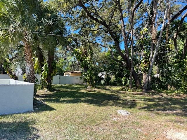 A grassy backyard features mature trees, a white fence, and a small shed in the distance — 741 28TH AVENUE S, ST PETERSBURG, FL