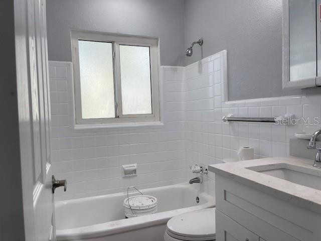 A bathroom features a white subway-tiled tub surround, a window, and a white vanity — 741 28TH AVENUE S, ST PETERSBURG, FL