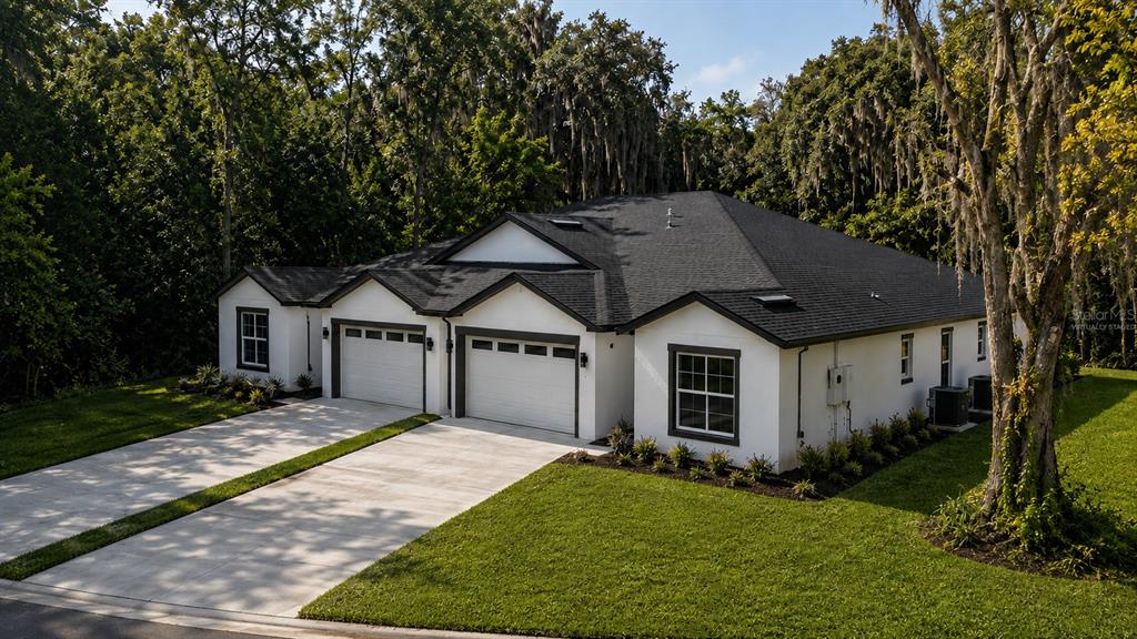 A white single-story house with a black roof and two garage doors sits near trees — 644 and 646 E FRANKLIN STREET, OVIEDO, FL