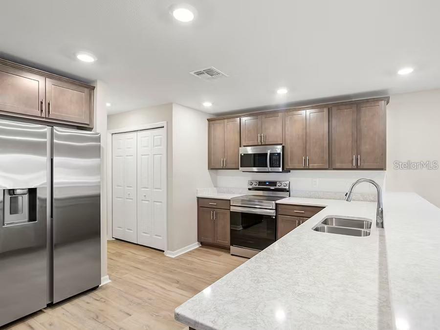 A kitchen features stainless steel appliances, wood cabinets, and light-colored countertops with a sink — 334 CHESAPEAKE DRIVE, ST CLOUD, FL