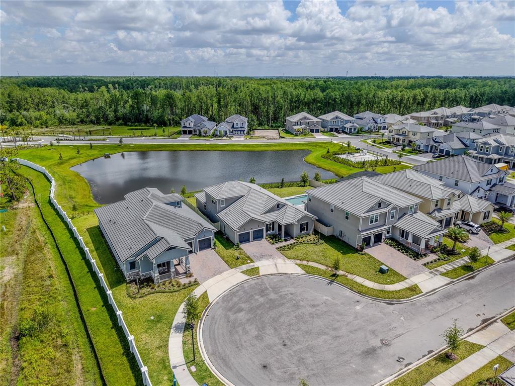 An aerial view shows several suburban houses with tiled roofs situated around a small lake — 14422 CREST PALM AVENUE, WINDERMERE, FL