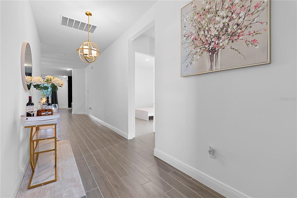 A hallway with wood-look tile flooring, a gold light fixture, and a console table — 14422 CREST PALM AVENUE, WINDERMERE, FL