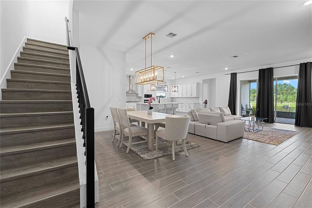 An open-concept living and dining area features wood-look tile floors and a staircase — 14422 CREST PALM AVENUE, WINDERMERE, FL