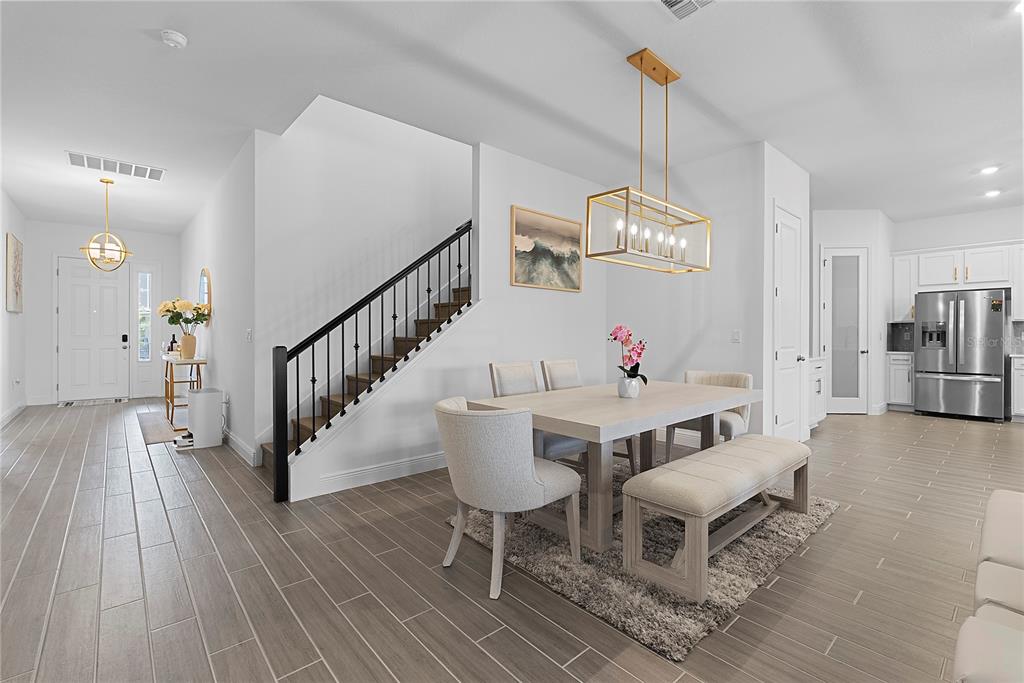 A dining area with a rectangular table, upholstered chairs, a bench, and a modern light fixture — 14422 CREST PALM AVENUE, WINDERMERE, FL