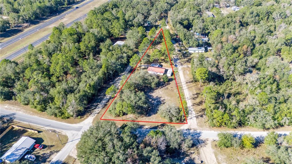 A single-story house with light siding and a red metal roof sits on a lot — 11216 NE 63RD PLACE, WILLISTON, FL