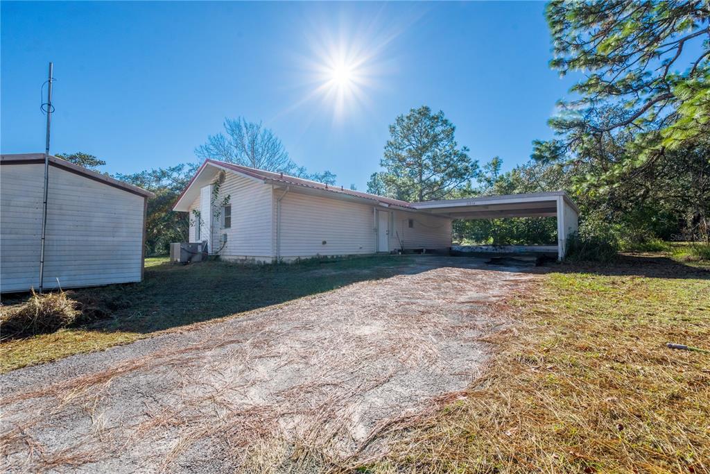 A single-story house with white siding, a metal roof, and an attached carport — 11216 NE 63RD PLACE, WILLISTON, FL