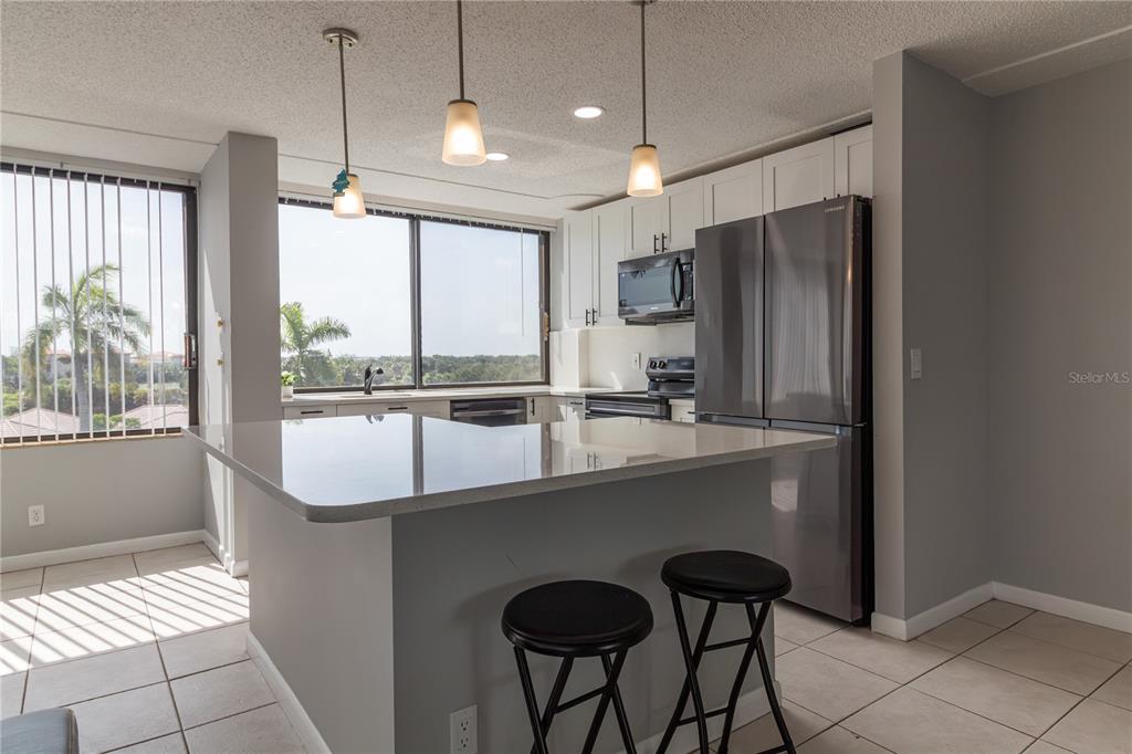 A kitchen with a gray island, stainless steel appliances, white cabinets, and a large window — 1500 PRESIDENTIAL WAY UNIT 401, WEST PALM BEACH, FL