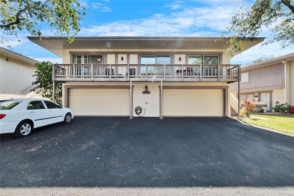 A two-story building exterior features a balcony above two garage doors and a paved driveway — 1849 BOUGH AVENUE UNIT D, CLEARWATER, FL
