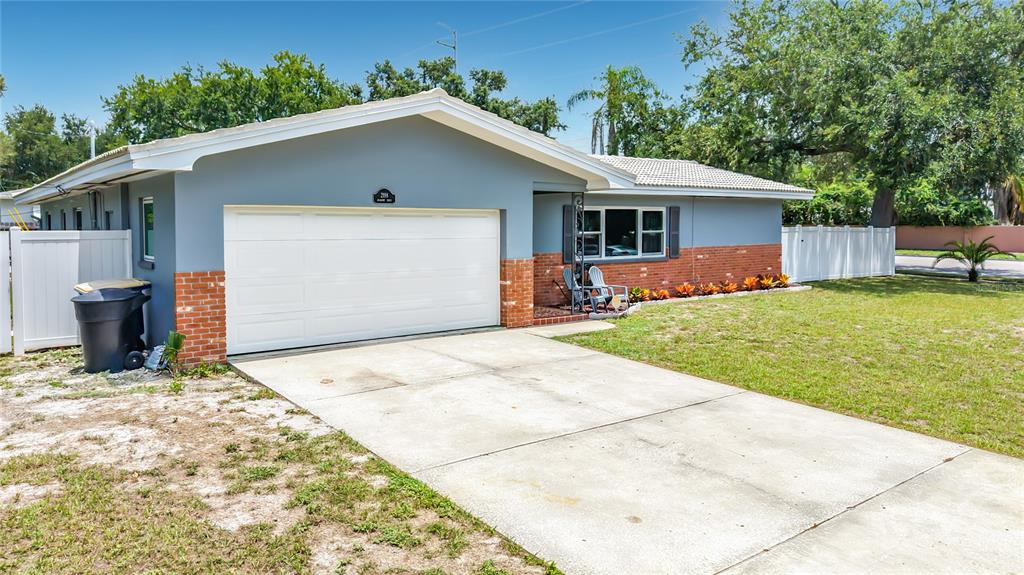 A single-story house with a white garage door, brick accents, and a concrete driveway — 2198 ACADEMY DRIVE, CLEARWATER, FL