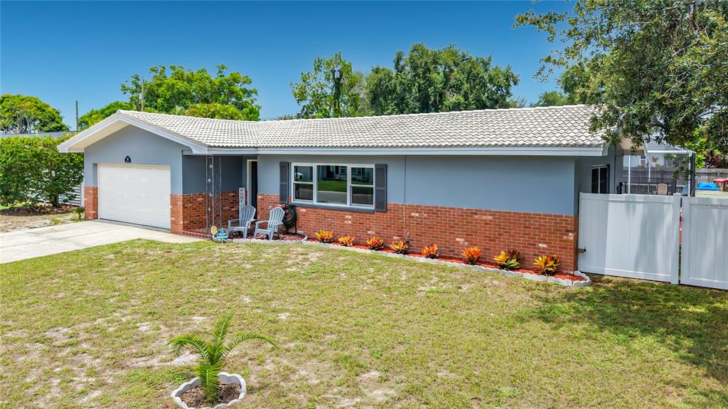 A single-story house features a gray exterior, brick lower walls, and a white tile roof — 2198 ACADEMY DRIVE, CLEARWATER, FL