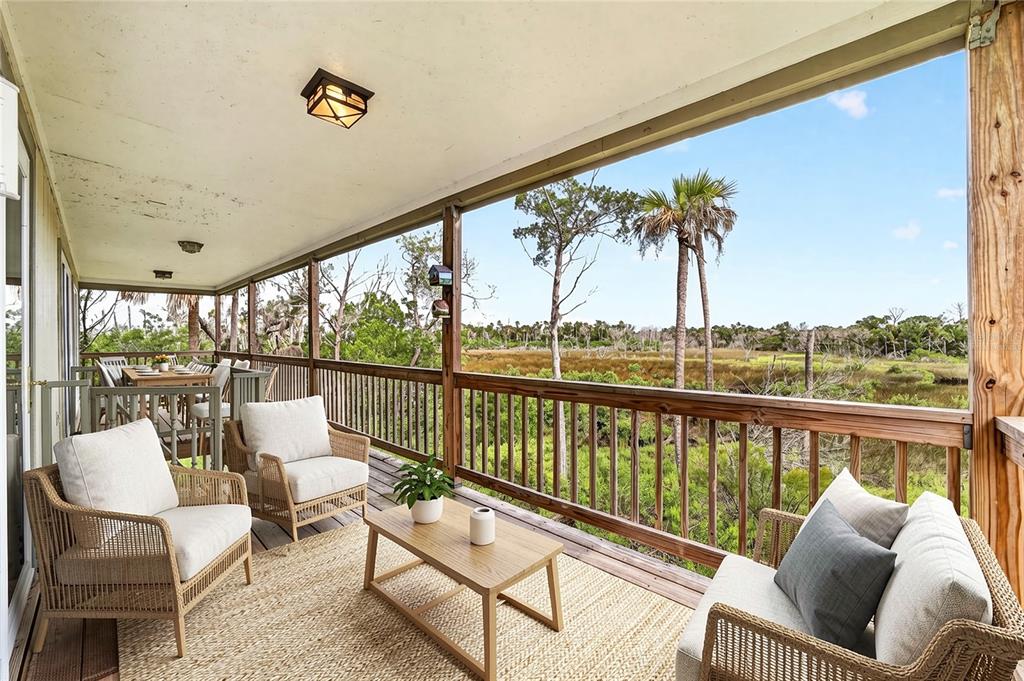 A covered wooden deck features outdoor seating and a view of a marshy landscape — 14141 W BOARDWALK LANE, CRYSTAL RIVER, FL
