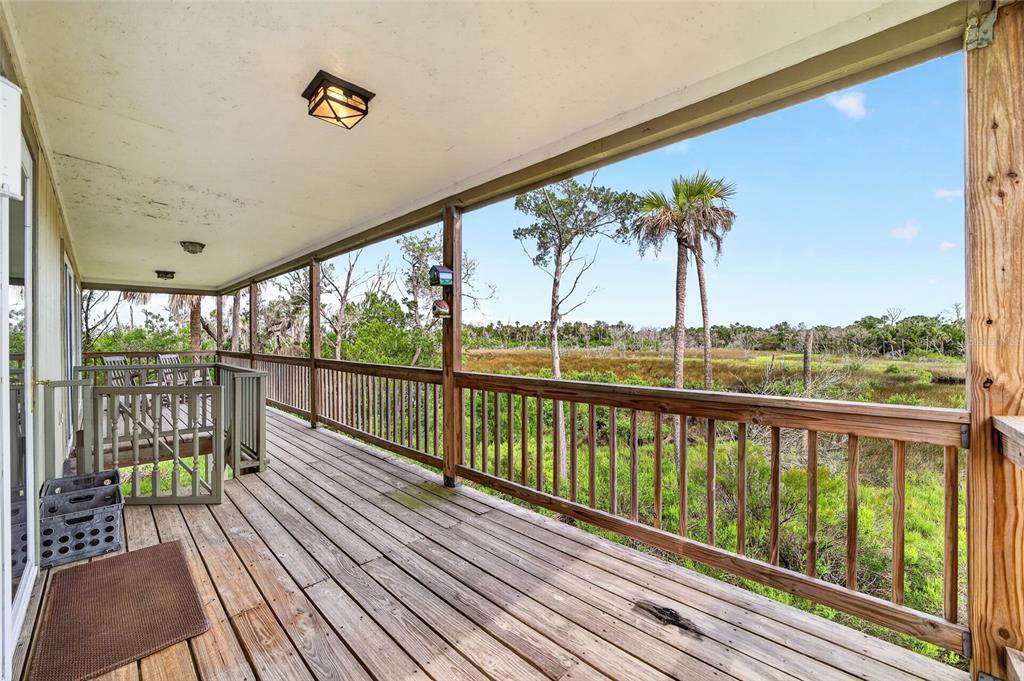 A wooden deck with a railing overlooks a grassy marsh area with palm trees — 14141 W BOARDWALK LANE, CRYSTAL RIVER, FL