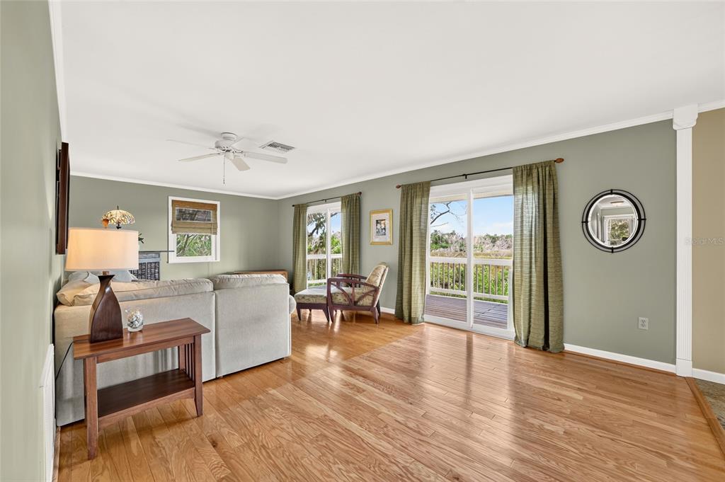 A living room with hardwood floors, sage green walls, a sectional sofa, and sliding glass doors — 14141 W BOARDWALK LANE, CRYSTAL RIVER, FL