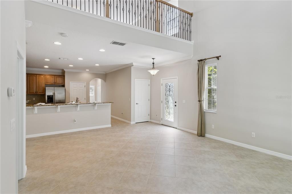 An open-concept living area features tile flooring, a kitchen with wood cabinets, and a lofted balcony — 624 VENICE PLACE, SANFORD, FL